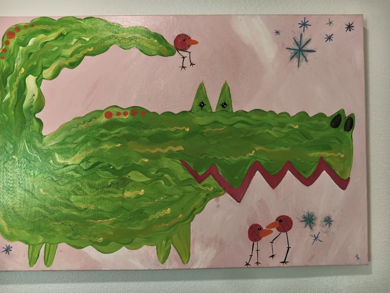 A child&rsquo;s painting of a green alligator hanging on the wall