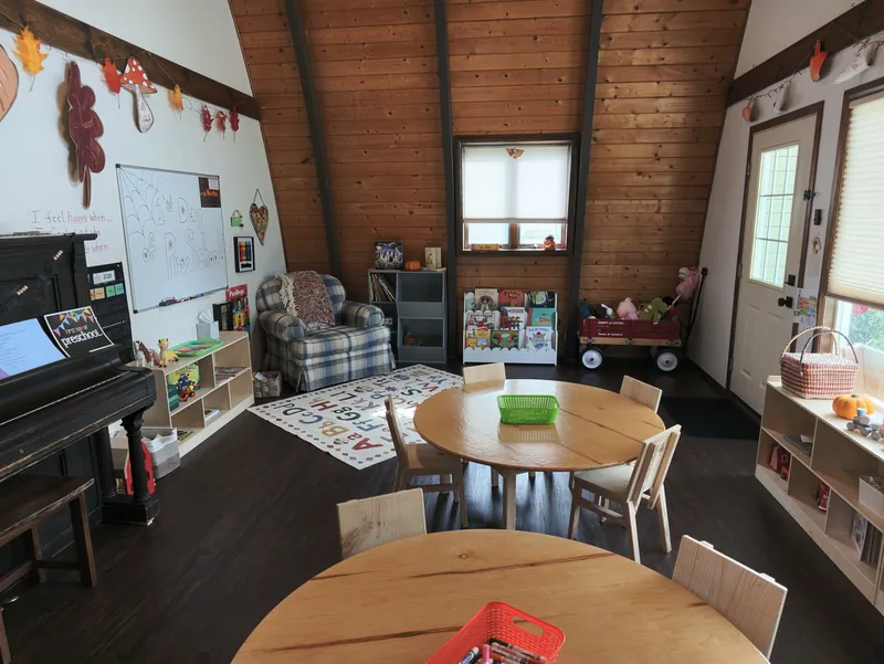 The A-frame room with round tables, the piano and the feelings chart on the wall