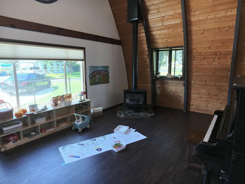 The A-frame room in afternoon light, with the wood stove and a window onto the yard